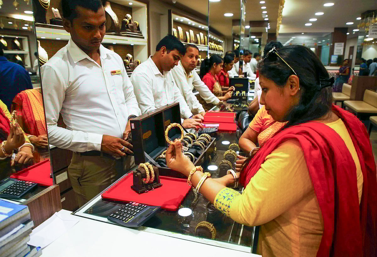 <div class="paragraphs"><p>A woman checks a gold ornament at a jewellery showroom. (PTI Photo)</p></div>