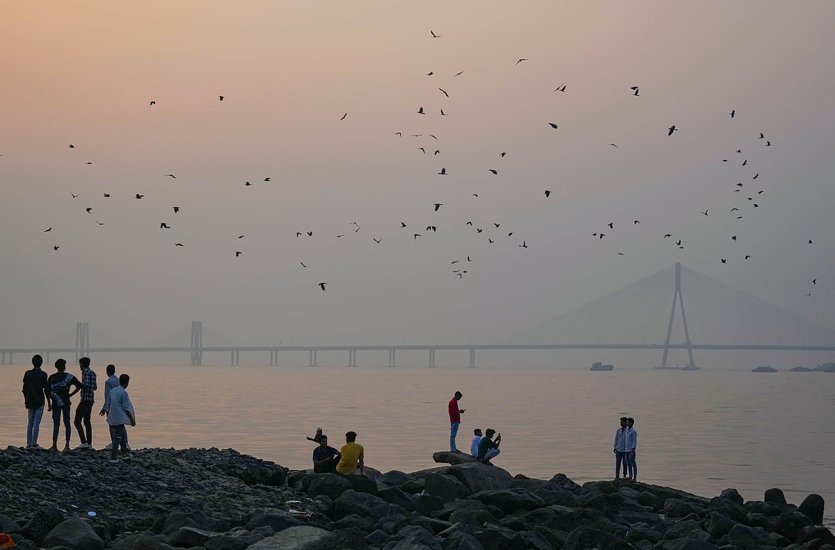 <div class="paragraphs"><p>Mumbai: People sit along the shoreline at Dadar Beach as the Bandra-Worli Sea Link remains shrouded in smog, in Mumbai. (PTI Photo/Kunal Patil)</p></div>