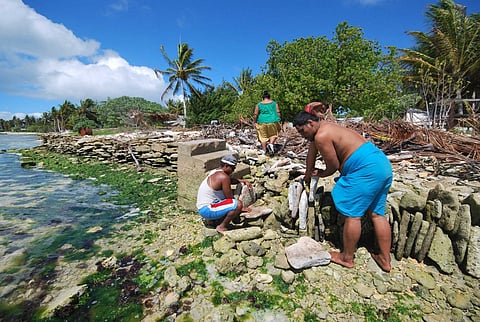 An undated handout picture released by the secretariat of the Pacific community shows inhabitants of Kiritimati coral atoll, part of the Republic of Kiribati, building a stone seawall as a defense against sea level rise caused by global warming. (Photo by SPC / AFP)