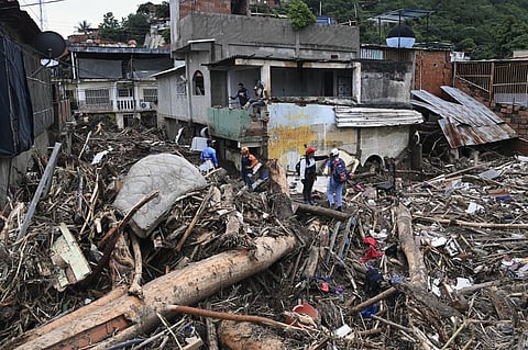 Rescuers and residents search through the rubble of destroyed houses for victims or survivors of a landslide during heavy rains in Las Tejerias, Aragua state, Venezuela, on 9 October 2022. (Photo by YURI CORTEZ / AFP)