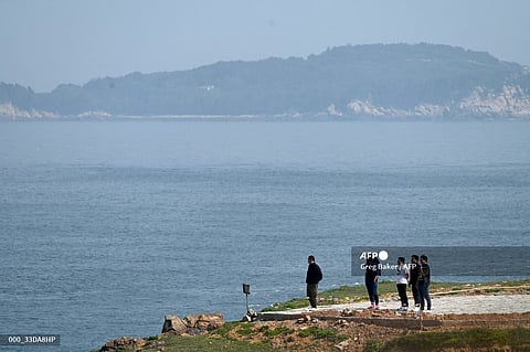 A group of men look out to the Taiwan Strait from Pingtan island, the closest point in China to Taiwan, in southeast China's Fujian province on 16 April 2023. (Photo by Greg Baker / AFP)