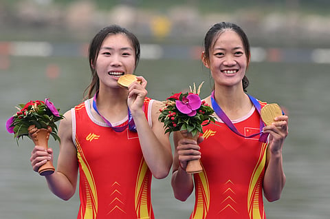 Gold medallists China's Zou Jiaqi and Qiu Xiuping pose for a photo during a medal ceremony after the women's light-weight double sculls final event of rowing during the 2022 Asian Games in Hangzhou in China's eastern Zhejiang province on 24 September 2023. (Photo by JUNG YEON-JE / AFP)