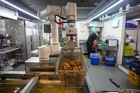 Kang's robot, composed of a simple, flexible mechanical arm, is capable of frying 100 chickens in two hours -- a task that would require around five people and several deep fryers. (Photo: Anthony Wallace / AFP)