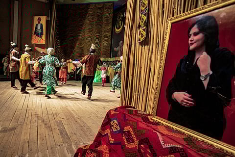 Syrian Kurds perform near a portrait of Mahsa Amini, which is displayed to mark the first anniversary of her death, during the Folk Dabke Festival in Rumaylan (Rmeilan) in Syria's northeastern Hasakeh province on 17 September 2023. (Photo by Delil SOULEIMAN / AFP)