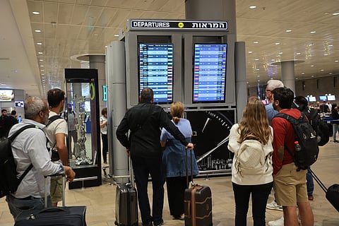 Passengers look at a departure board at Ben Gurion Airport near Tel Aviv, Israel, on 7 October 2023, as flights are canceled because of the Hamas surprise attacks. The conflict sparked major disruption at Tel Aviv airport, with American Airlines, Emirates, Lufthansa and Ryanair among carriers with cancelled flights. (Photo by GIL COHEN-MAGEN / AFP)