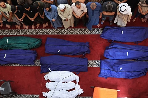 People gather at a mosque to pray over the bodies of the Abu Quta family and their neighbours, killed in Israeli strikes on the Palestinian city of Rafah in the southern Gaza Strip, during their funeral on 8 October 2023. (Photo by SAID KHATIB / AFP)