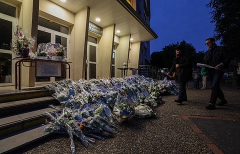 People pay their tribute beside flowers layed outside the Gambetta high school for French teacher Dominique Bernard who died in a knife attack on October 13, in Arras, north of France on October 16, 2023. Dominique Bernard, 57, was stabbed to death at the school in Arras in what the government has described as an Islamist terror attack. (Photo by DENIS CHARLET / AFP)