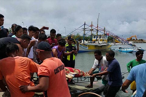 This handout photo taken on 3 October 2023 and released by the Philippine Coast Guard on 4 October 2023 shows personnel retrieving the body of a crew member of a Filipino fishing boat in Infanta, after their boat was "rammed" by a foreign commercial vessel on 2 October about 160 kilometers northwest of Scarborough Shoal, off the Philippines' main island of Luzon.  (Photo by Handout / Philippine Coast Guard (PCG) / AFP) 