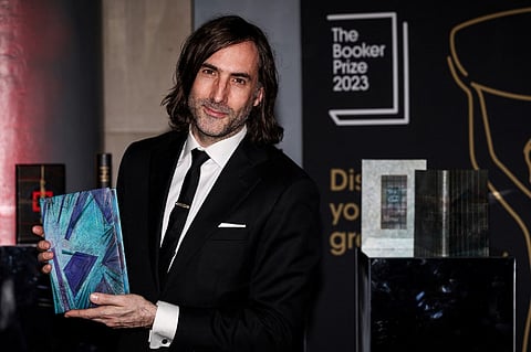 Irish writter Paul Lynch and Booker Prize 2023 shortlisted author poses with his specially bound book copy "Prophet Song" on the red carpet upon arrival for the Booker Prize Award announcement ceremony, at the Old Billingsgate, in central London, on 26 November 2023. (Photo by Adrian DENNIS / AFP)