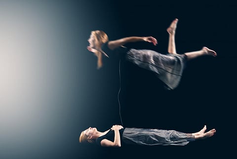 Woman lying down in a dark place with an image of her body floating above her. | PHOTOGRAPH COURTESY OF medical news today