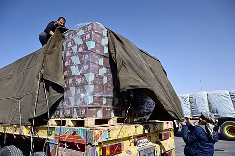 A truck driver refastens his humanitarian aid cargo after inspection by Israeli security upon arriving from Egypt on the Israeli side of the Kerem Shalom border crossing with the southern Gaza Strip on December 22, 2023, amid the ongoing conflict between Israel and the Palestinian militant group Hamas. (Photo by Alberto PIZZOLI / AFP)