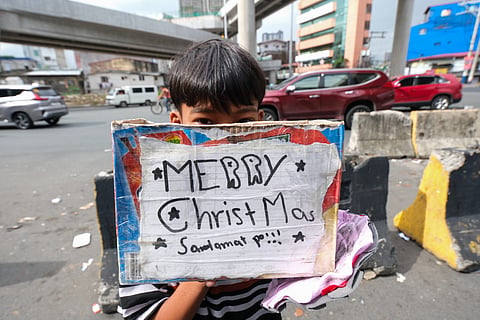 Share sunshine Tyke ingenuously brandishes a box with his uniquely designed greeting to convince passersby to fork out an aguinaldo. | PHOTOGRAPH BY KING RODRIGUEZ FOR THE DAILY TRIBUNE