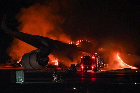 A Japan Airlines  passenger plane is seen on fire on the tarmac at Tokyo International Airport at Haneda on 2 January 2024. A Japan Airlines plane was in flames on the runway of Tokyo's Haneda Airport on January 2 after apparently colliding with a coast guard aircraft, television reports said. (Photo by Richard A. Brooks / AFP)