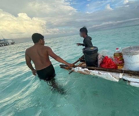 A Filipino soldier assists Rosalon Cayon (right) at the Rizal Reef Detachment of the AFP after he is rescued by four Chinese fishermen. | PHOTOGRAPH COURTESY OF AFP WESCOM