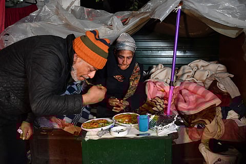 Leila and another homeless man share the Friday night dinner offered by the "Restaurant of Love", a charitable initiative launched three years ago to help feed the growing number of Tunis' homeless, in her cardboard shelter where she and her dogs sleep, in Tunis on January 26, 2024. According to World Bank data, growth of Tunisia's highly indebted economy stood at just 1.2 percent in 2023, while inflation stood at 8.3 percent in 2022. With the economic woes exacerbated by the Covid-19 pandemic and soaring food prices in the wake of the war in Ukraine, poverty rates are on the rise in the population of 12 million. (Photo by FETHI BELAID / AFP)