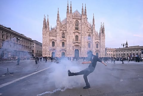Milan Cathedral in Italy stands amid smoke during clashes linked to cost-of-living and anti-government protests on October 17, 2026.