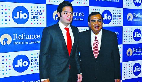 Mukesh Ambani and Akash Ambani standing in front of a Jio Platforms branded backdrop