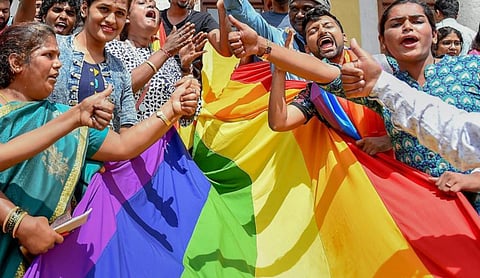 Members of the LGBTQ+ community hold a rainbow flag. | Image Source: PTI