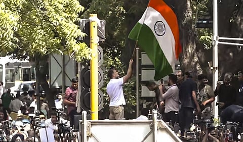 Rahul Gandhi holds the national flag atop a police barricade during the INDIA bloc march to the Election Commission, New Delhi, Tuesday, October 6, 2026. (Screengrab via PTI)