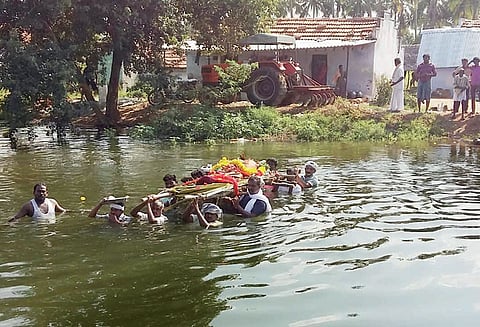 பாடையுடன் பிணத்தை சுமந்துகொண்டு வாய்க்காலை கடக்கும் கிராமமக்கள்