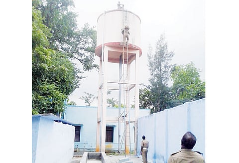 டெங்கு கொசு ஒழிப்பு பணிக்காக பள்ளிக்கூட குடிநீர் தேக்க தொட்டியில் ஏறிய வாலிபர் இறங்க முடியாமல் தவிப்பு