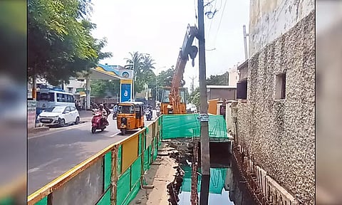 ஆதம்பாக்கத்தில் மழைநீர் கால்வாயில் சாய்ந்து நிற்கும் மின்கம்பத்தை தாங்கி பிடிக்கும் பொக்லைன் எந்திரம் - பொதுமக்கள் அச்சம்