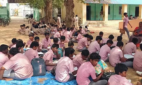 காட்டுப்புத்தூர் அரசு மேல்நிலைப்பள்ளிக்கு போதிய வகுப்பறை வசதி இல்லாததால் மரத்தடியில் அமர்ந்து படிக்கும் அவலம்