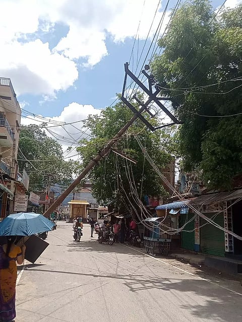 கூடலூர் மெயின்பஜார் வீதியில் சாலையில் திடீரென சாய்ந்த மின்கம்பம்