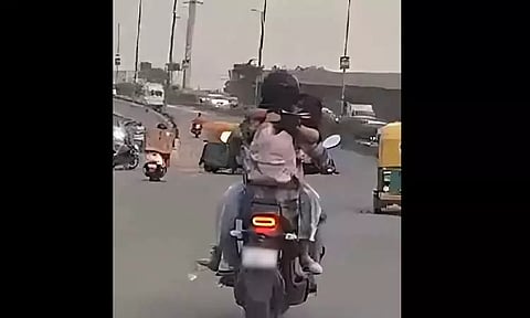 பெட்ரோல் டேங்க் மீது அமர்ந்து வாலிபரை கட்டிப்பிடித்தவாறு பைக்கில் சென்ற இளம்பெண் - ரூ.11 ஆயிரம் அபராதம் விதித்த போலீசார்