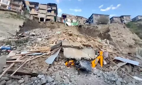 An escavator crushed under the debris after a building collapsed at Kabaddi Nalla, in Kargil