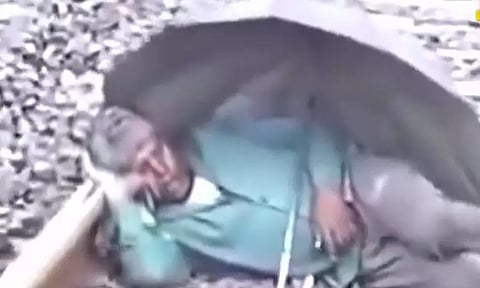 ரெயில் தண்டவாளத்தில் குடையை விரித்தபடி படுத்து உறங்கிய நபர்