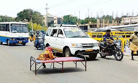 வயதான தாயை கட்டிலுடன் சாலையின் நடுவே அமர வைத்த நபர்; தேனியில் பரபரப்பு