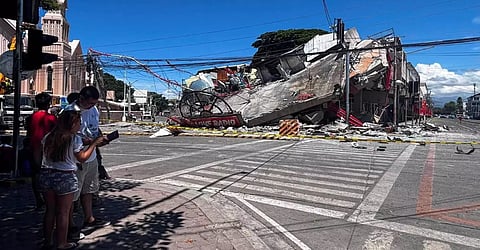 People stand near a collapsed building after a magnitude 7.8 quake in General Santos, Philippines, June 8, 2026.
