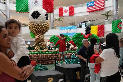 Shoppers stand in front of balloon flags of countries participating in the FIFA World Cup finals at a shopping center in Guadalajara, Mexico, Tuesday, June 9, 2026. 