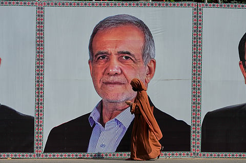 A woman walks past a welcoming billboard featuring Iranian President Masoud Pezeshkian along a roadside in Islamabad, Pakistan, Tuesday, 23 June 2026.