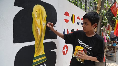 A boy paints a mural in the streets of Dhaka.