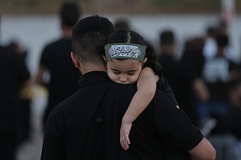 A girl wearing an Ashoura headband rests on her father's shoulder during a sermon marking the third day of Ashoura, the Shiite Muslim commemoration of the 7th-century death of Imam Hussein, the grandson of the Prophet Muhammad, in the southern port city of Tyre, Lebanon, 19 June 2026.