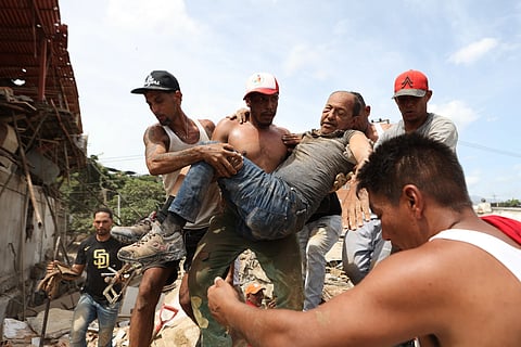  Neighbors carry a man rescued from the rubble of a collapsed building the day after earthquakes struck La Guaira, Venezuela,