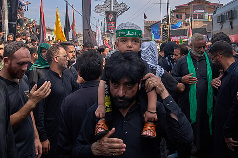 A Kashmiri Shiite Muslim carries a child as he mourns during an Ashura procession, the tenth day of Muharram, in Srinagar, Indian controlled Kashmir, 26 June 2026. 
