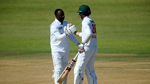 Zimbabwe's batsman Innocent Kaia, left, shakes hand with his teammate Zimbabwe's Brian Bennett, after scoring 100 runs during second day of the Test match between Zimbabwe and Bangladesh in Harare, Zimbabwe on Monday