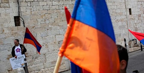 Armenians hold their national flag during a ceremony to commemorate the mass killings of Armenians by the Ottoman Empire, in Jerusalem, Israel, Friday, April 24, 2015. 