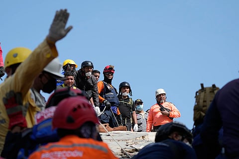 Residents and rescue workers pause during a search for survivors in Catia la Mar, Venezuela