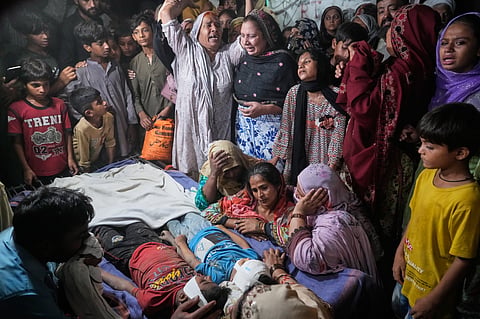 Women mourn next to the bodies of their children killed after the roof of a tutoring center under-construction collapsed, on the outskirts of Lahore, Pakistan, 30 June  2026.