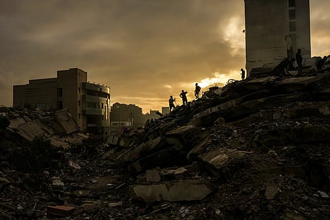 Men searching for survivors atop a pile of rubbles