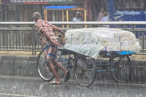 A laborer pushes a cargo rickshaw van covered with a plastic sheet through heavy monsoon rain in the Karwan Bazar area of Dhaka on July 6, 2026. 