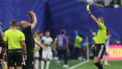 Egypt coach Hossam Hassan is shown a yellow card by referee Francois Letexier as he makes anti-racism gesture