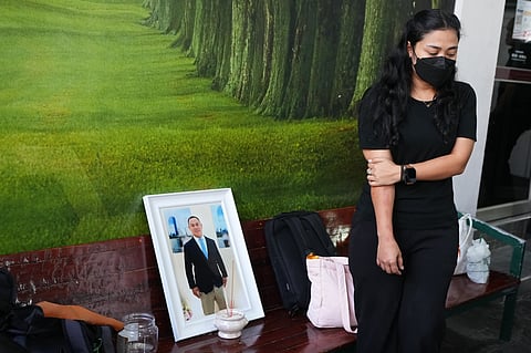 A relative of a musician Preutthipong Pudmon victim, a victim in a music bar fire, stands beside his portrait as she receives his body at a police hospital in Bangkok, Thailand, 15 July 2026.