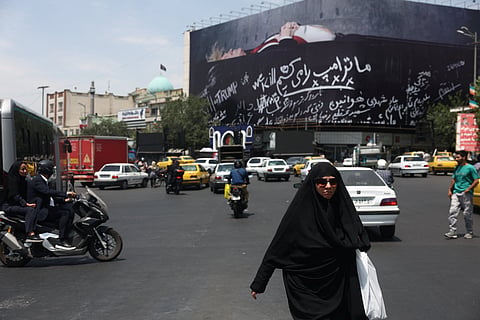 A woman walks next to a billboard depicting US President Donald Trump laid in a coffin, in Tehran, Iran, July 18, 2026.