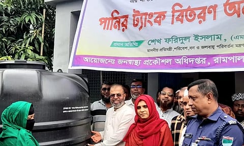 State Minister Sheikh Faridul Islam hands over a rainwater harvesting tank to a beneficiary in Rampal, Bagerhat.