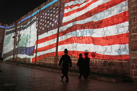 A US flag is seen through a hole torn in an Israel national flag, as they wave in the wind at a horse ranch, near the southern Israeli town of Sderot, Friday, Nov. 20, 2020. 